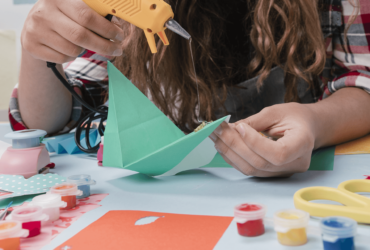 A person making paper boats with glue and scissors.