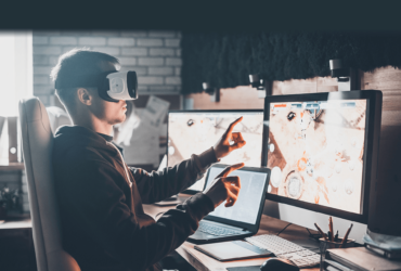 A man wearing goggles and holding a laptop