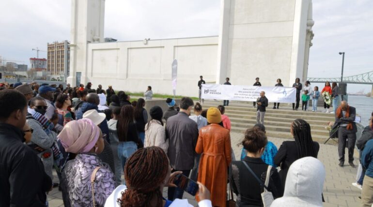 Crowd gathering at outdoor event with speakers.