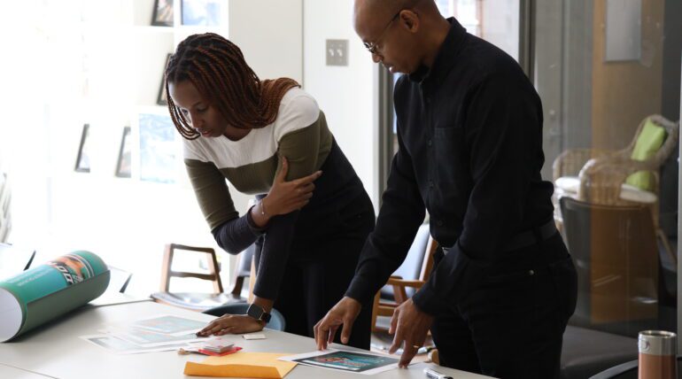 Two people collaborating over printed materials.