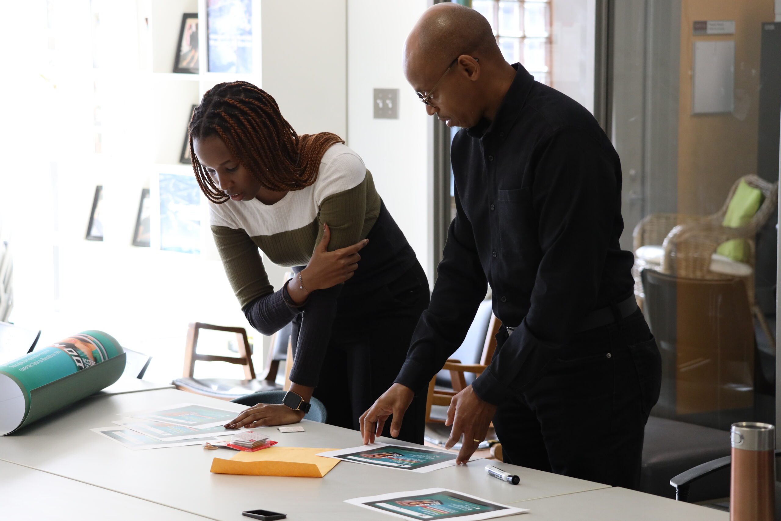 Two people standing at a table with papers and pens.