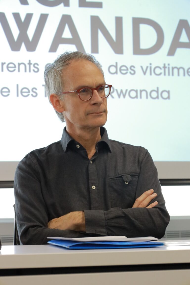 A man with glasses is sitting in front of a projector.