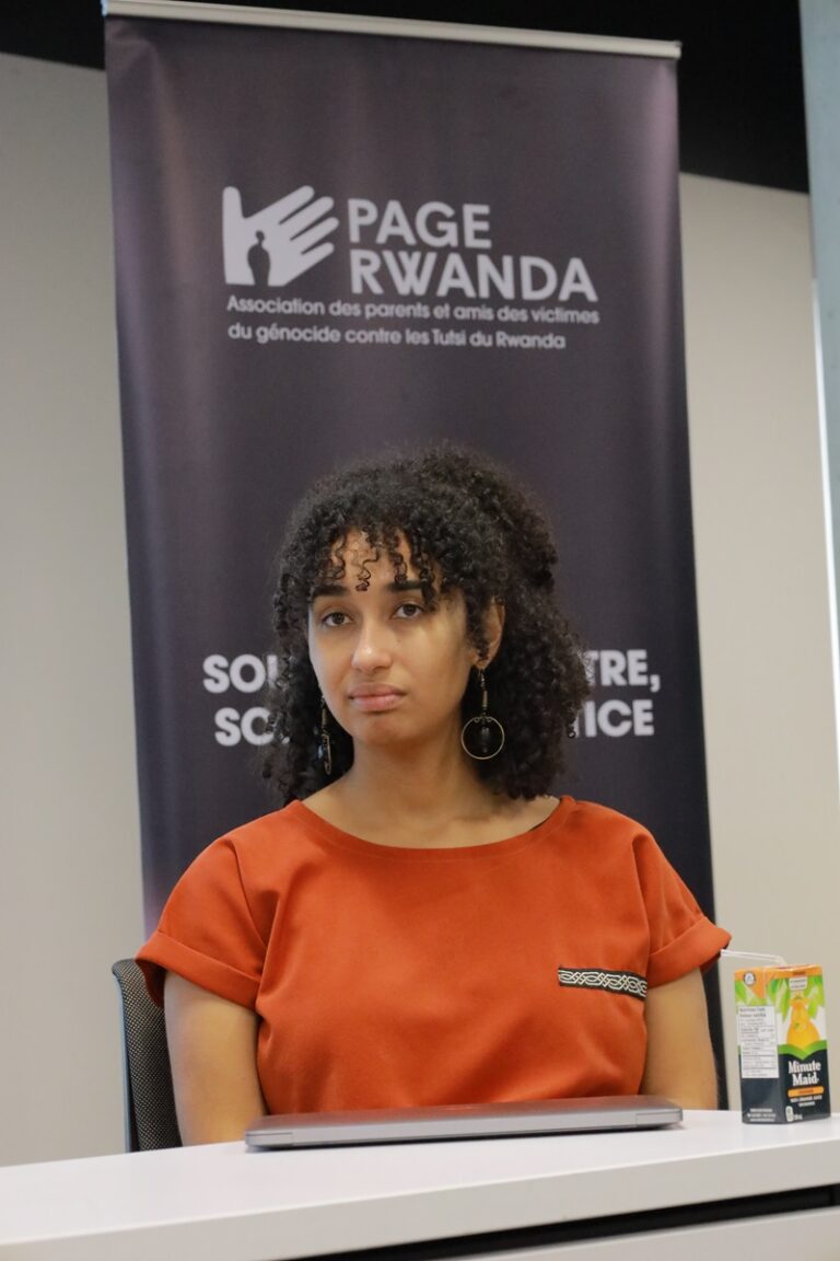 A woman in an orange shirt is sitting at a table