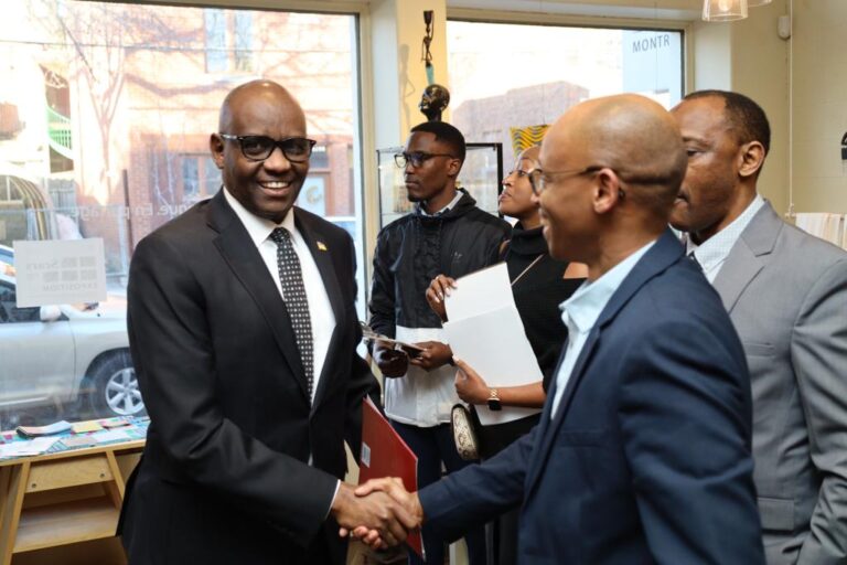 Two men shaking hands in a room with other people.