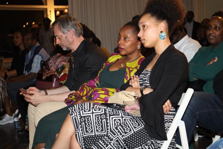 A group of people sitting on chairs in front of a wall.