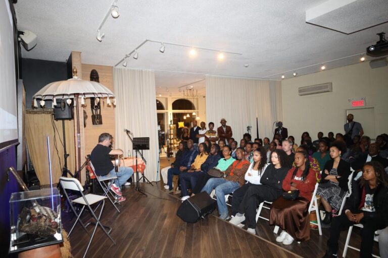 A group of people sitting in chairs and listening to an artist.