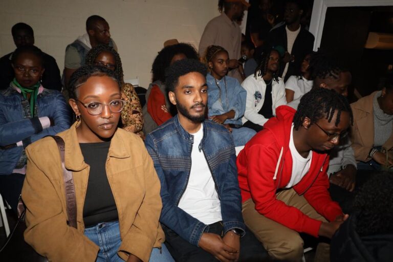A group of people sitting in front of a wall.