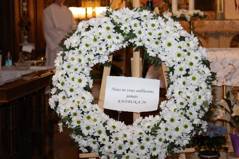 A wreath of white flowers with a sign on top.
