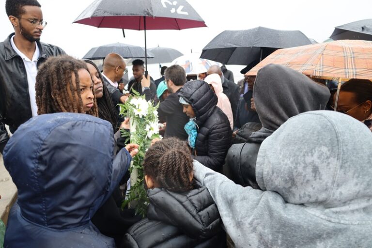 A crowd of people holding umbrellas and flowers.