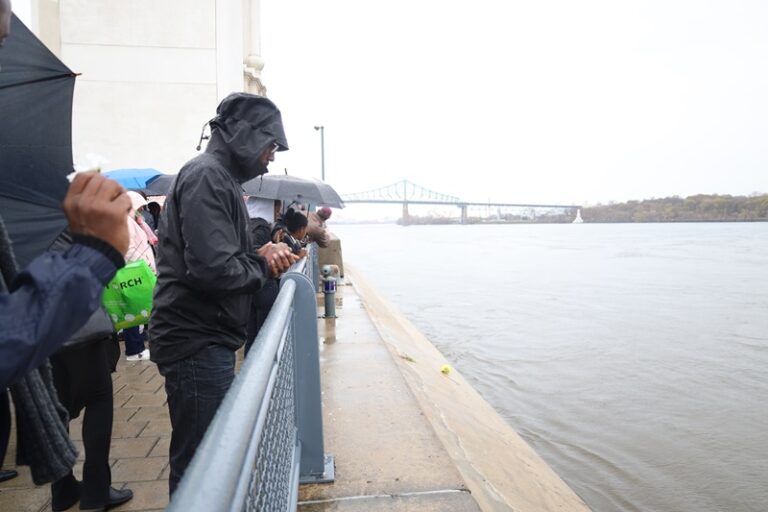 A person with an umbrella standing on the side of a river.