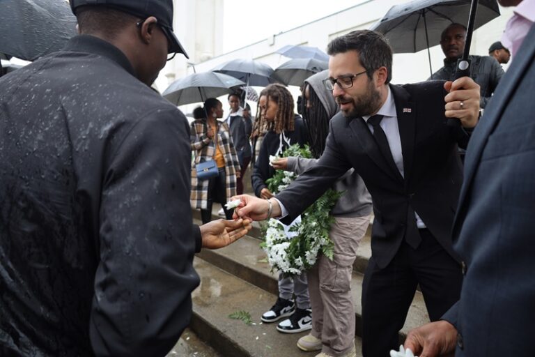 A man in a suit and tie shaking hands with another person.