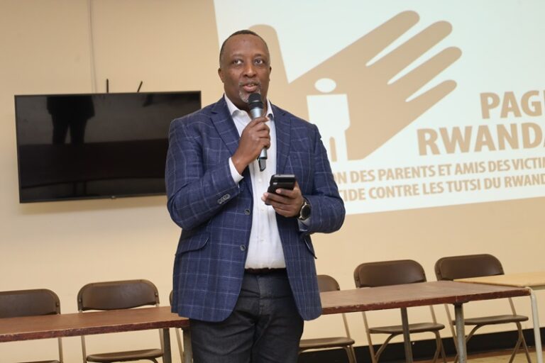 A man holding a phone and speaking into a microphone.