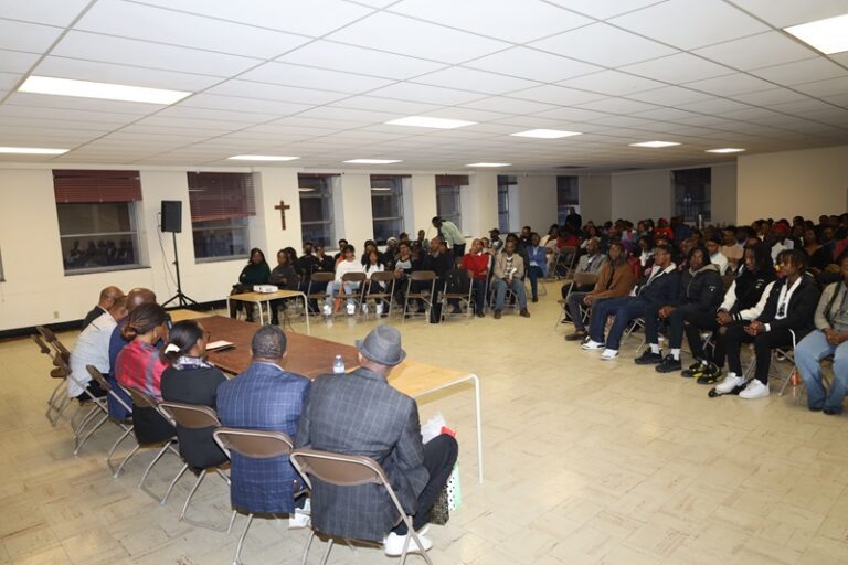 A group of people sitting in chairs and listening to speakers.