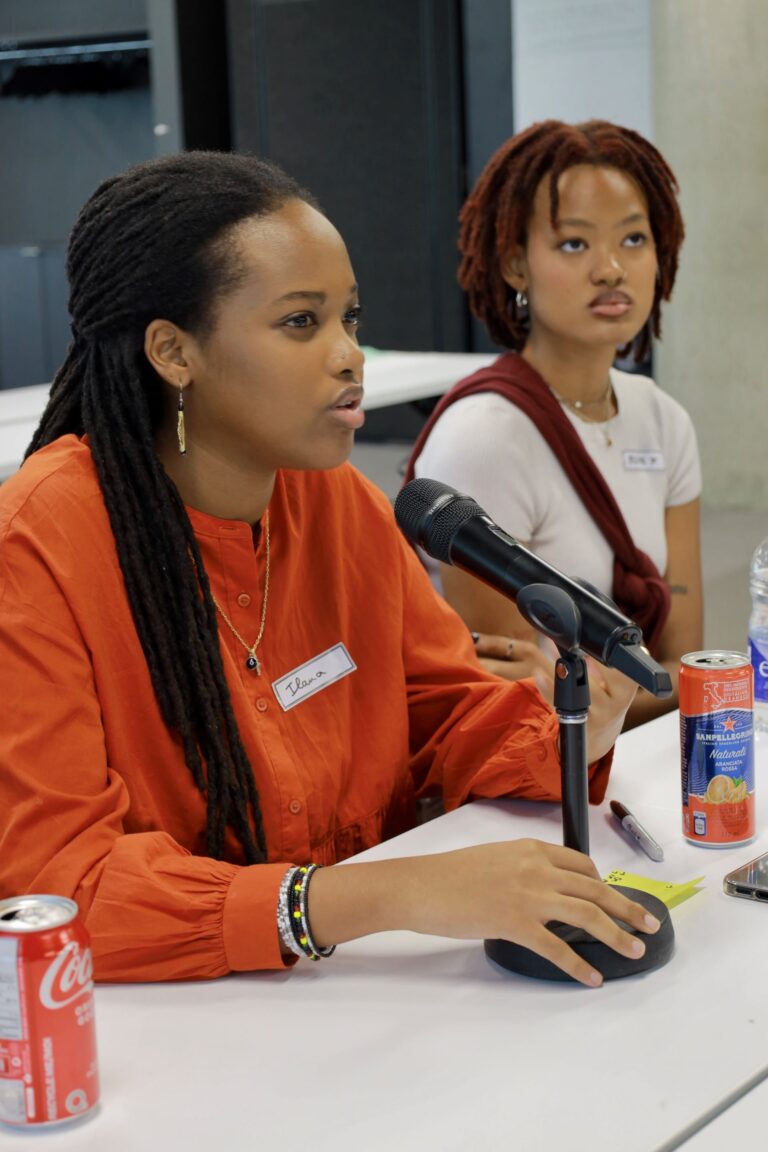 Two women sitting at a table with microphones.