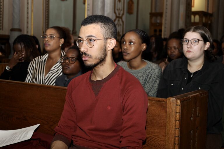 People seated in a church pew attentively.