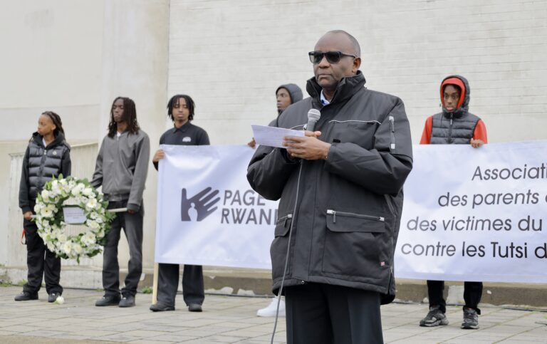 Man speaking at outdoor memorial event.