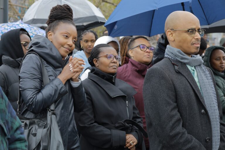 Group of people standing under umbrellas.