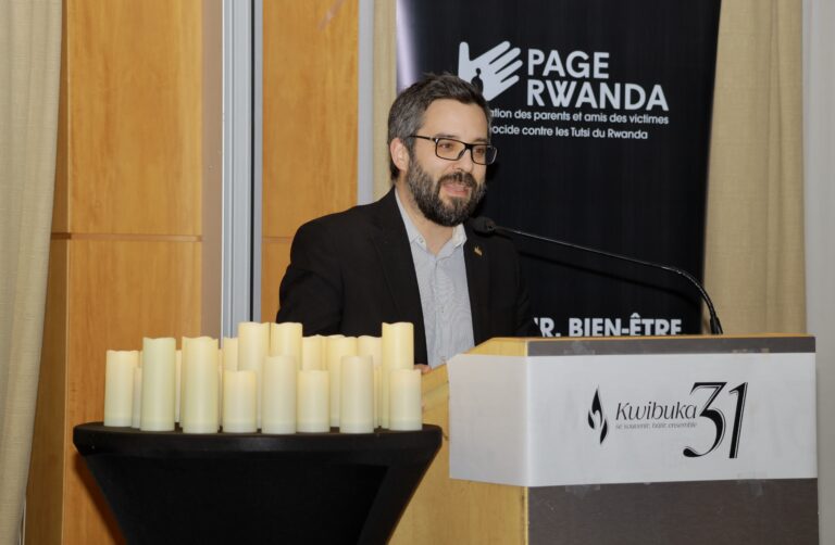 Man speaking at a commemorative event podium.