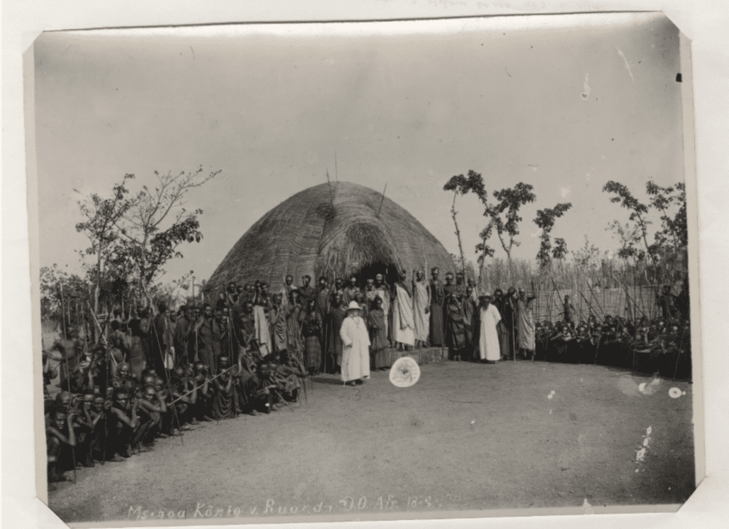 Group gathered outside traditional thatched hut.